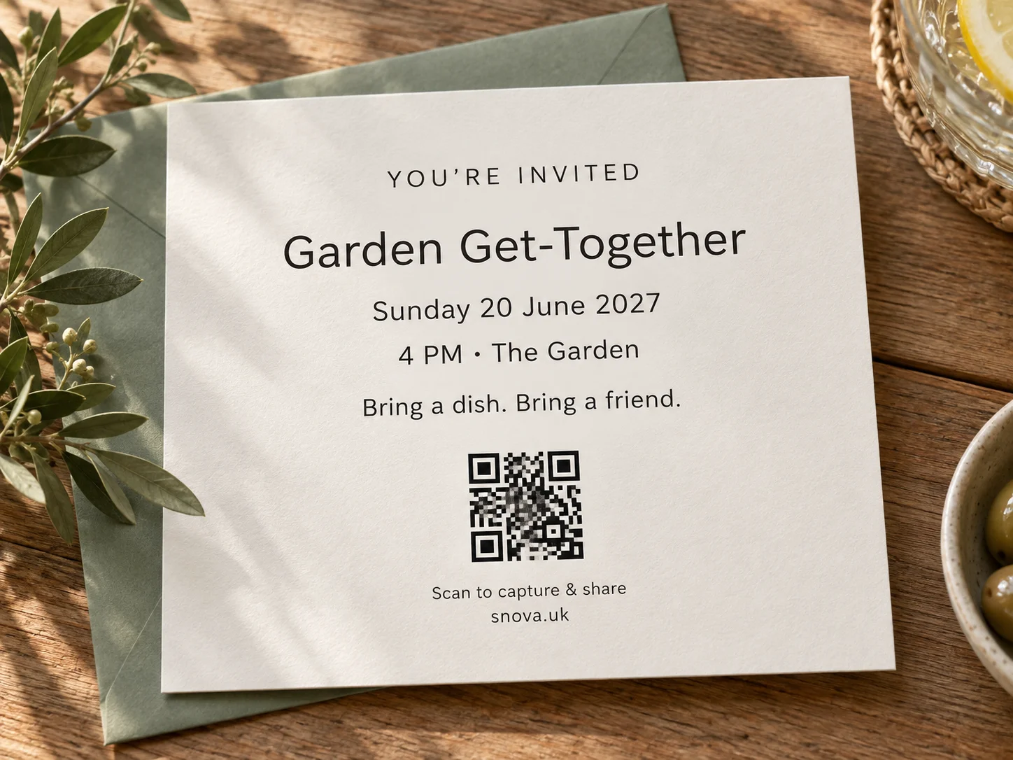 A printed Garden Get-Together invitation card with QR code on a wooden table